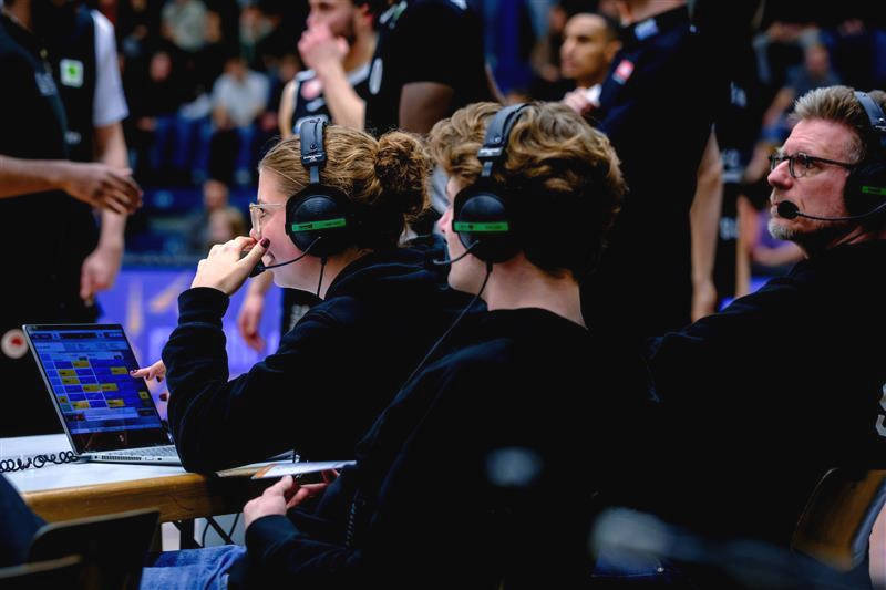 Scouting-Team mit Headsets und Laptop am Spielfeldrand.